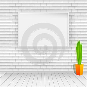 White brick wall with white wooden floor. On the wall hangs an empty white picture. On the floor is a pot with green plant