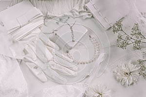 White bridal accessories for wedding background with pearls, white satin ribbons and lace, gloves, bracelet,flat lay for fashion