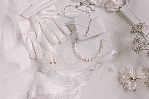 White bridal accessories for wedding background with pearls, white satin ribbons and lace, gloves, bracelet,flat lay for fashion