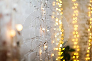 White brike wall with blurred background with bokeh lights, electric garland.