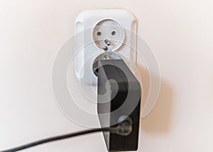 White broken electrical socket fell out of the wall. The socket is torn from the wall.