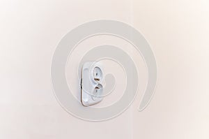 White broken electrical socket fell out of the wall. The socket is torn from the wall.