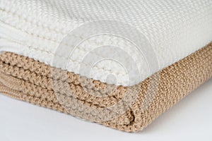 White and bronze plaids are stacked on a white surface.