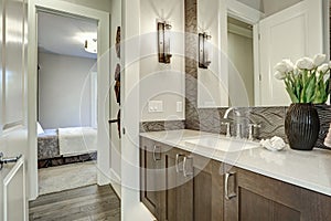 White and brown bathroom boasts a nook filled with taupe vanity