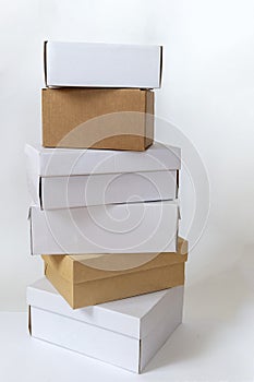 White and brown carton boxes of different size standing on each other as a high tower.