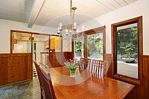 White and brown dining room with fresh flowers on the table set and walls with wooden plank trim.