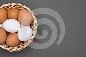 White and brown eggs in the basket on a gray table. Easter. Top view