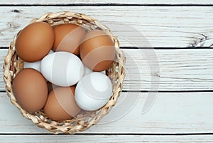 White and brown eggs in the basket on the table. Easter. Top view