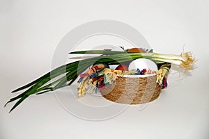 White and brown eggs and a bunch of green onions on a checkered napkin in a bowl on a white background