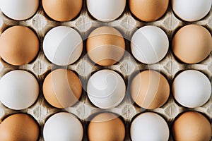 white and brown eggs laying in egg carton, full