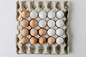 white and brown eggs laying in egg carton on white background