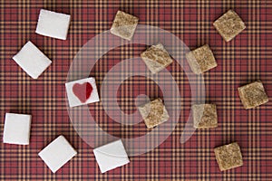 White and brown sugar cubes with a red heart on one of them. Top view. Diet unhealty sweet addiction concept