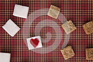 White and brown sugar cubes with a red heart on one of them. Top view. Diet unhealty sweet addiction concept photo