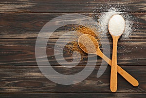 White and brown sugar in wood spoon on brown background