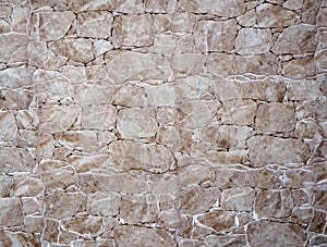 White and brown wall made of irregular polished stones