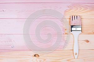 White brush on wooden board painting into pink color.