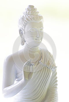 White Buddha with natural light in white scene.