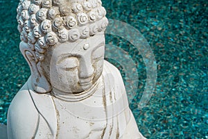 White Buddha statue on azure water background. Founder of Buddhism. Close up