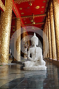 White Buddha statue in a buddhist monestary with red and gold