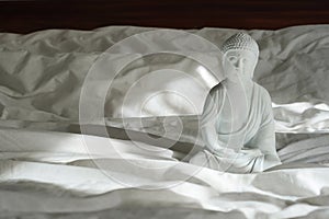 White buddha statue with sunlights on the bed, interior design detail in modern home