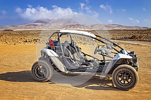 White buggy in stone and sandy desert on volcanic island photo