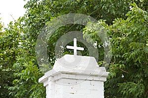 White building with a cross on top in a park