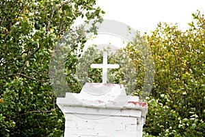 White building with a cross on top in a park