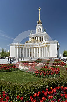 White building Pavilion No.1 of VDNKh exhibition in Soviet Union Empire style with colomns, golden decoration, red tulips