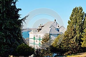 white building on the shore in a thicket of trees, against the backdrop of a lake and mountains