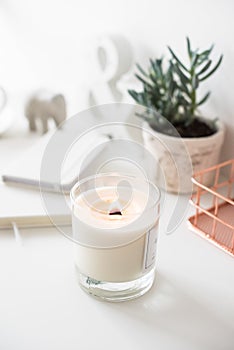 White burning candle on table, home interior decorations