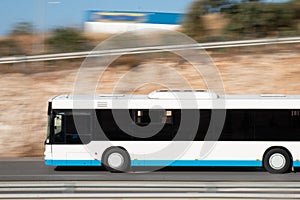 White bus moving fast along the street on a motion blurred background. Bus driving on freeway