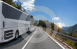 A white bus rides along the highway against the backdrop of a beautiful landscape