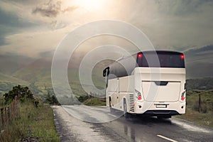 White bus on a small narrow country road. Mountains in a fog in the background. Transportation in rural area. Dramatic nature
