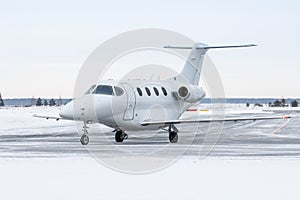 White business jet taxiing on airport taxiway in winter