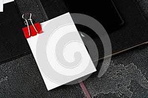 White businesscards united with a paper clip on a black rough background