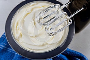 White butter cream in bowl with mixer whisk