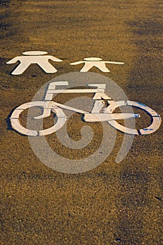 White bycicle and pedestrian symbols on a path. Pictogram imitating of walking figures, parent and child