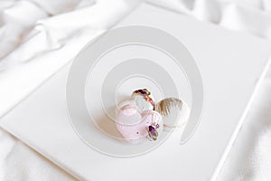 A white cake lies on a white plate on a light background. Light macaroons. Delicious pastries