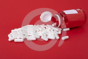 White calcium pills pouring out of red bottle