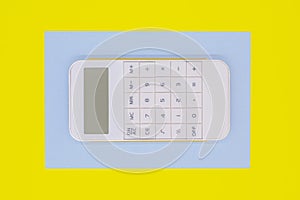 White calculator in a blue frame on a yellow background. finance