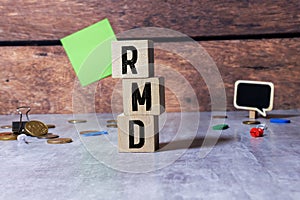 On a white calculator, next to a magnifying glass and a black pen, wooden cubes marked RMD Required Minimum