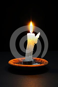 White candle against black background.
