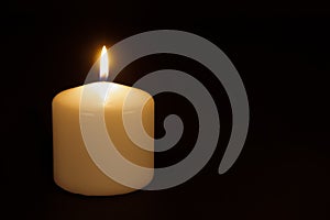 White candle burning against a black background