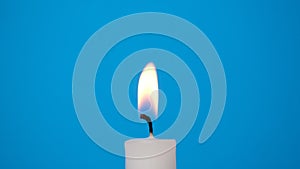 A white candle burning on a blue background. A candle is blown out, beautiful smoke from a blown out candle on a blue