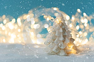 White candle on Christmas fir tree shape on snowy and defocused lights background. Christmas or New Year celebration concept. Copy