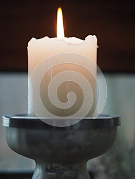 Burning lonely white candle with a fire flame