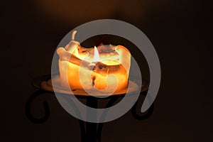 White candle with flame and melting wax on an iron candlestick a