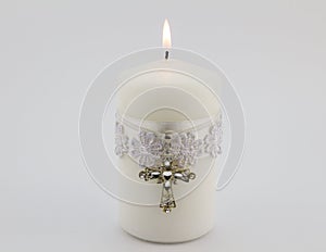 White candle with lace, ribbon and Christian cross pendant isolated on white background