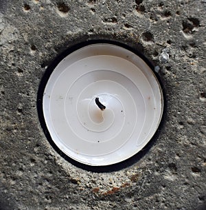 White candle in porous rock hole. photo