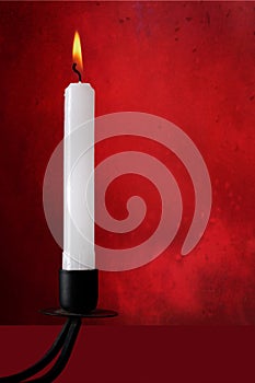 White candle in old black candlestick, over red.